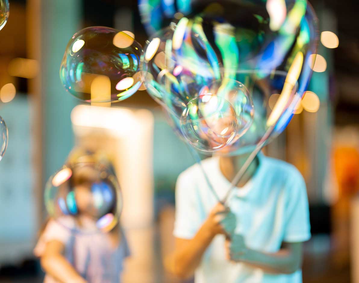 Two small children blowing large soap bubbles.