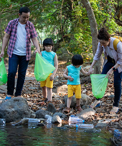 A family with two young children collecting trash from water