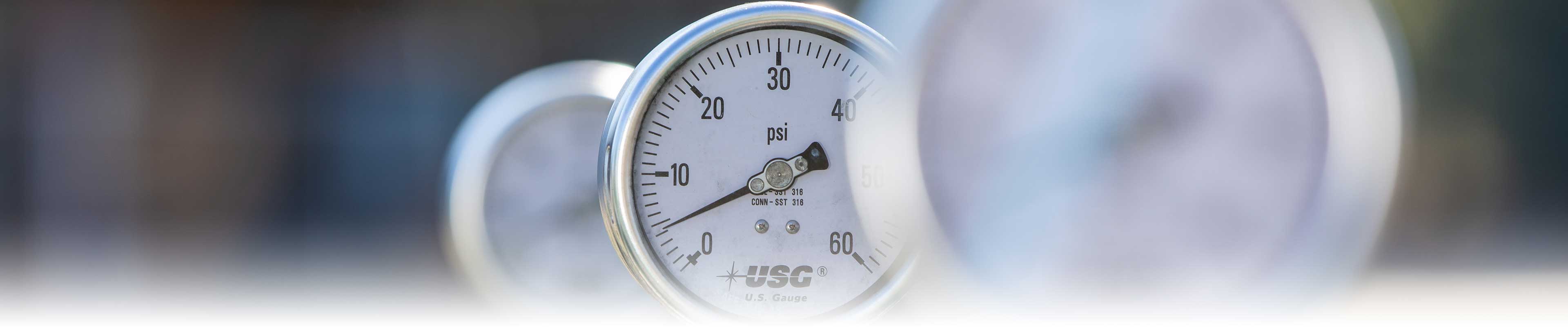 A close-up of three water pressure gauges, with only middle one in focus.