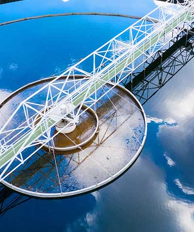 A wastewater treatment plant tank reflecting a cloudy sky.