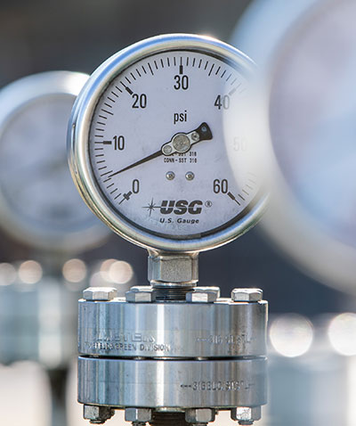 A close-up of three water pressure gauges, with only middle one in focus.