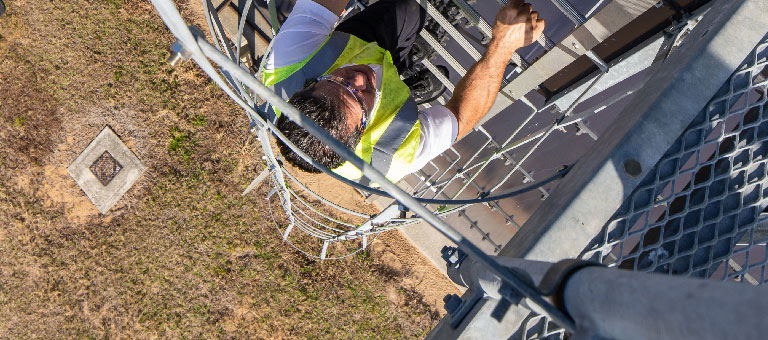 A utility worker climbing a large water tank ladder.