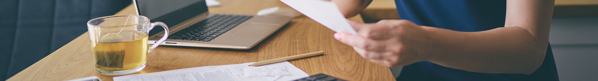 A close-up of a woman looking at a bill, and doing household accounts.