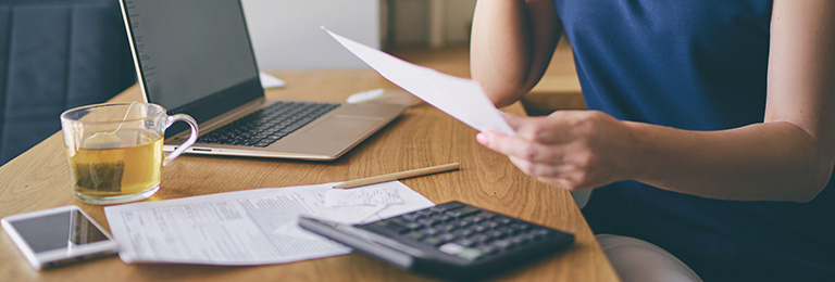 A close-up of a woman looking at a bill, and doing household accounts.