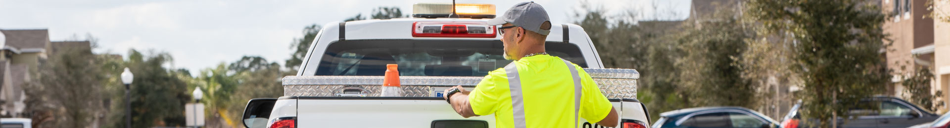 A worker standing behind a utility service pickup truck.