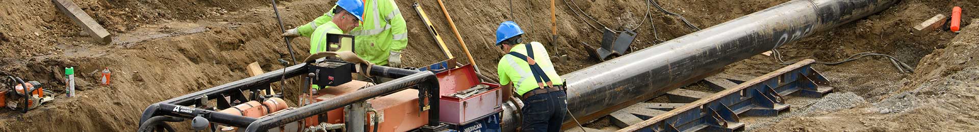 Workmen laying a watermain in a deep excavation.