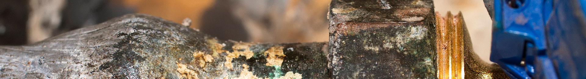 A close-up of a lead pipe and water meter in a home.