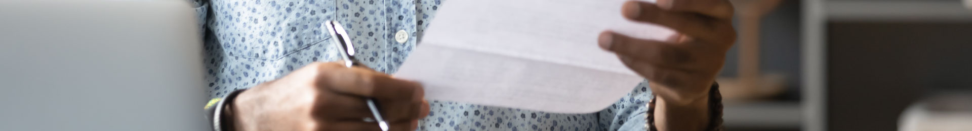 A man holding and looking at a paper bill.