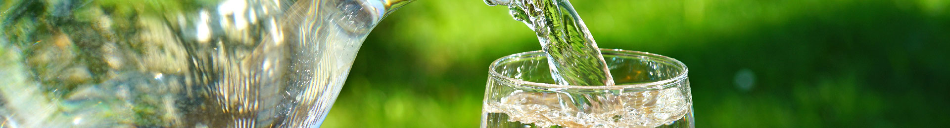 Crystal clear water being poured from a pitcher into a glass.