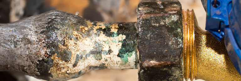 A close-up of a lead pipe and water meter in a home.