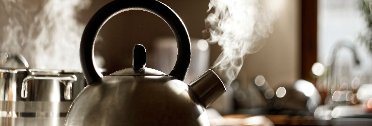 A boiling kettle releasing steam in a kitchen.