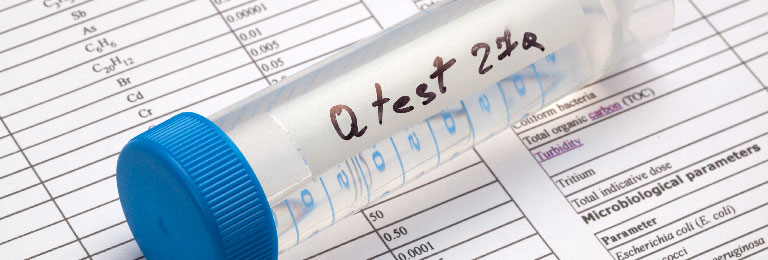 A testing vial of water sitting on a page of lab results.