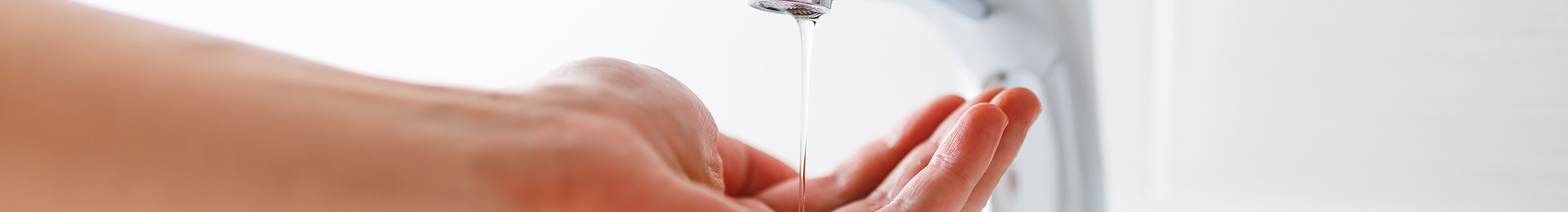 A close-up of a hand under a low flowing bathroom tap.