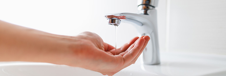 A close-up of a hand under a low flowing bathroom tap.